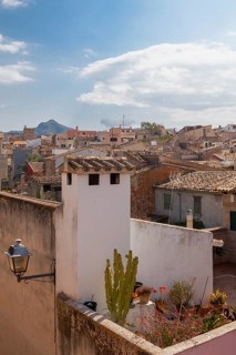 Mediterranean village with stone houses and green terraces under a slightly cloudy sky, Alcudia,