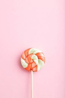 Single lollipop candy on pink pastel background. copy space, top view, flat lay