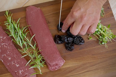 Swabian cuisine, preparation of lamb with prunes, raw lamb, rosemary, herbs, sliced garlic, lemon