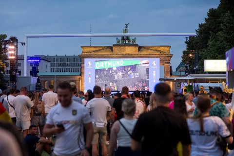 Fassball fans celebrate and gather information in the fan zone at the Brandenburg Tor after the