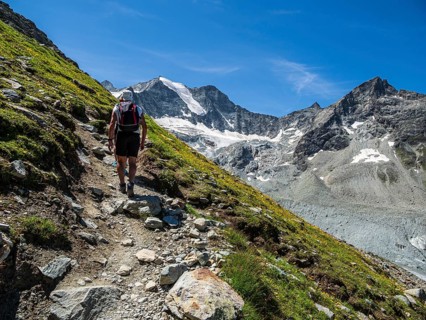 Hiking path up to mountain hut Cabane de Moiry, hiking tourists, Moiry glacier in the back, Valais,