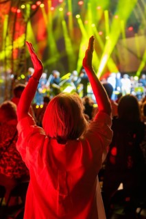 Person applauds at a night concert with red lights on stage, Klostersommer, Calw Hirsau, Black