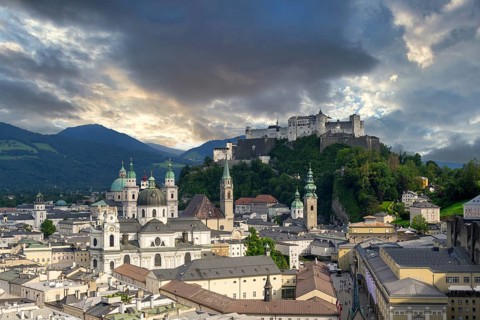 Panorama of Salzburg's historic city centre at dusk with Hohensalzburg Fortress and dramatic