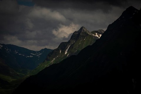 Grassy summit with remnants of snow and dramatic clouds, Lech, Lechquellengebirge, Vorarlberg,