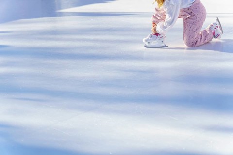 Girl lacing up her skates in an ice rink