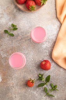 Sweet strawberry liqueur in glass on a gray concrete background and orange textile. top view, flat