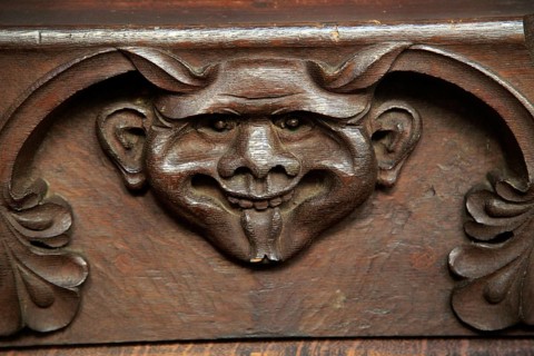 Wooden carved devil face in bench seat, Ufford church, Suffolk, England, UK