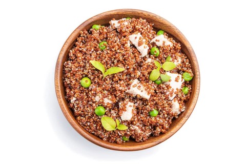Quinoa porridge with green pea and chicken in wooden bowl isolated on a white background. Top view,
