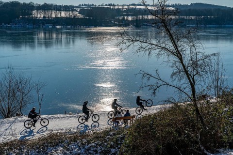 Winter in the Ruhr area, Lake Baldeney, snow-covered, partly frozen lake, walkers on the lakeside