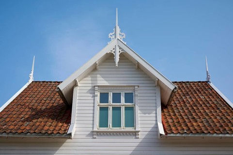 A traditional house with a red tiled roof and white wooden gable under a blue sky, Sandnes, Fylke
