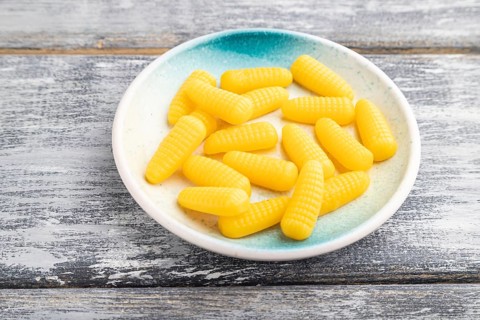 Jelly corn candies on gray wooden background. side view, close up