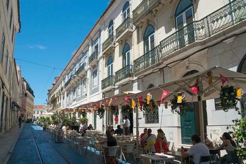 A street café in front of historic buildings in an old town under a blue sky with a relaxed