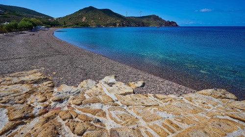 Beach with pebbles, mountains and clear blue water under a blue sky, Lambi beach, pebble beach,
