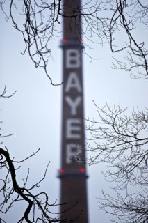 Bayer lettering on a chimney behind bare branches, Bayer AG, agrochemical and pharmaceutical