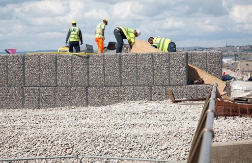 Repair work on steel mesh cages known as gabions which provide coastal defence at Chiswell, Isle of