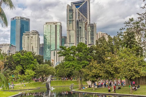 The city park with a small lake with buildings on background