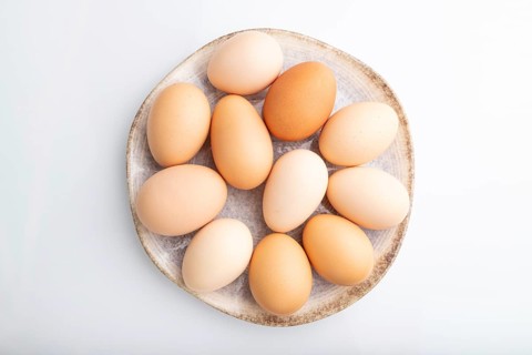 Pile of colored chicken eggs on plate isolated on white background. top view, flat lay, close up