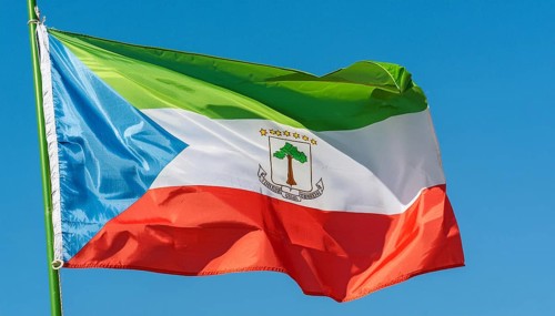 The flag of Equatorial Guinea flutters in the wind, isolated against a blue sky