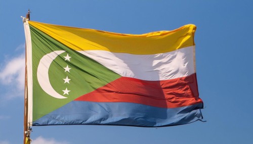 The flag of the Comoros flutters in the wind, isolated against a blue sky