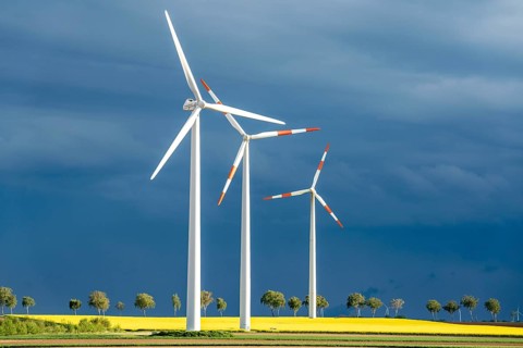 Wind turbines on a rape field, dark rain clouds, in the Rhenish lignite mining area, near