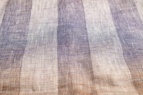Fragment of smooth brown and violet linen tissue. Side view, natural textile background and texture