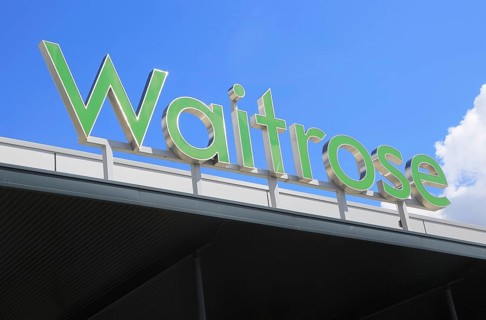 Green Waitrose supermarket shop sign against blue sky, Ipswich, Suffolk, England, UK