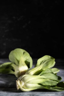Fresh green bok choy or pac choi chinese cabbage on a gray wooden background. Hard light, contrast,