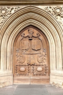 Detail of wooden door and stone arched entrance to the abbey church, Bath, Somerset, England,
