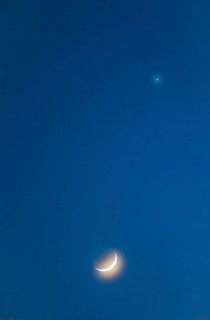 Narrow crescent moon with a halo (corona) and visible moon disc shortly after the new moon, evening