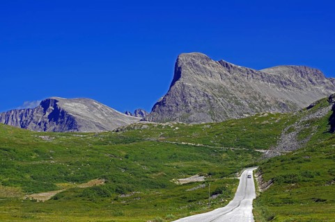 A clear road leads through a green mountain landscape under a blue sky, Trollstigen, Andalsnes,