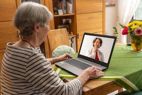 Symbolic image of telemedicine, patient speaking to a doctor in a video conference from home