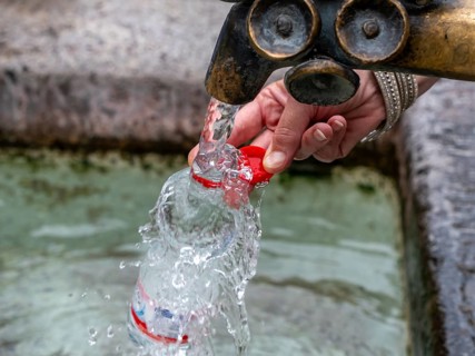 Water fountain, a woman fills drinking water into a small plastic bottle, Munich, Bavaria, Germany,