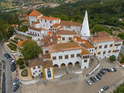 Aerial view of a historic castle with striking white towers and surrounding gardens, Royal Palace,