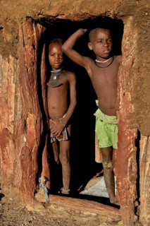 Himba children standing at the door of their hut, Omohanja, Kaokoland, Kunene, Namibia, Africa