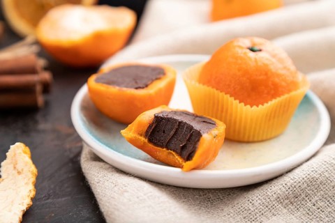 Truffle chocolate tangerine candies on a black concrete background and linen textile. Side view,