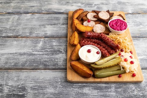 Set of snacks: sausages, toast, sauerkraut, marinated onion and cucumber, baked potato on a cutting