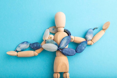 Wooden mannequin with blue agate beads on blue pastel background. copy space, isolated, luxury, bad