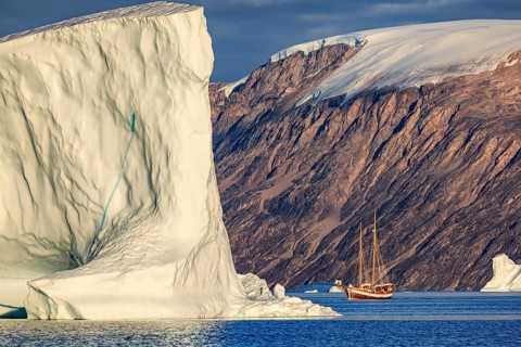 Sailing boat, ship in fjord in front of large icebergs and mountains, evening light, Scoresby