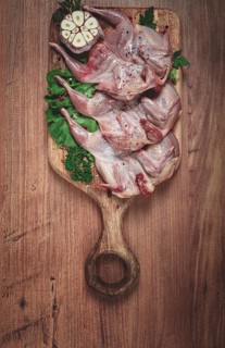 Raw quail meat, on a cutting board, with spices and herbs, top view