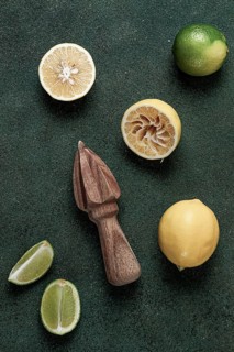 Wooden citrus reamer, manual lemon juicer, made of acacia wood, with citrus fruits on the table,