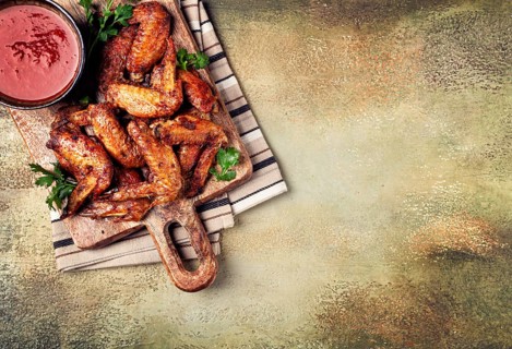 Fried in the oven, chicken wings, with spices, tomato sauce, on a cutting board, gray background,