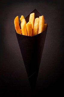 French fries, in black paper packaging, on a black background, close-up, selective focus