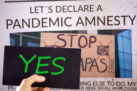 Symbolic image of Pandemic Amnesty: a section of a symbolic newspaper with a sign reading YES held