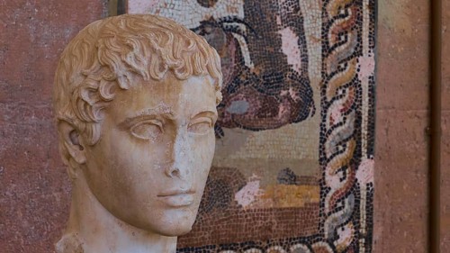 Classical portrait of an ancient marble bust, head of a young man, against a mosaic background,