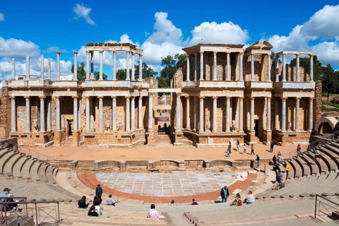 Ancient Roman theatre with ruins and columns in the background, people exploring the historic site