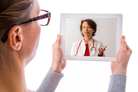 Symbolic image of telemedicine, patient speaking to a doctor in a video conference from home