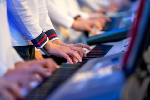 Young people, children play on many keyboards, simultaneously, electronic clarinet, at a concert