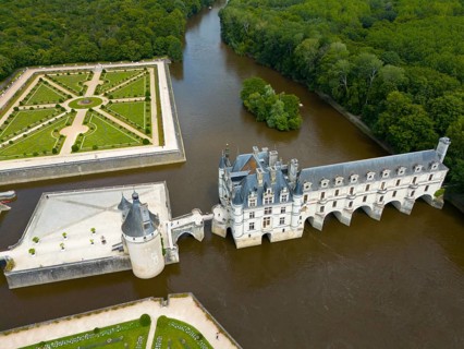 Historic castle with a Renaissance garden by a river and surrounded by dense forest, aerial view,