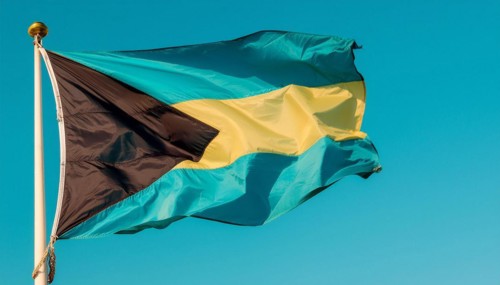 The flag of the Bahamas flutters in the wind, isolated against a blue sky