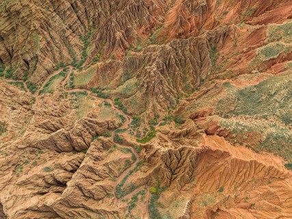 Eroded mountain landscape, top-down, canyon with red and orange rock formations, aerial view,